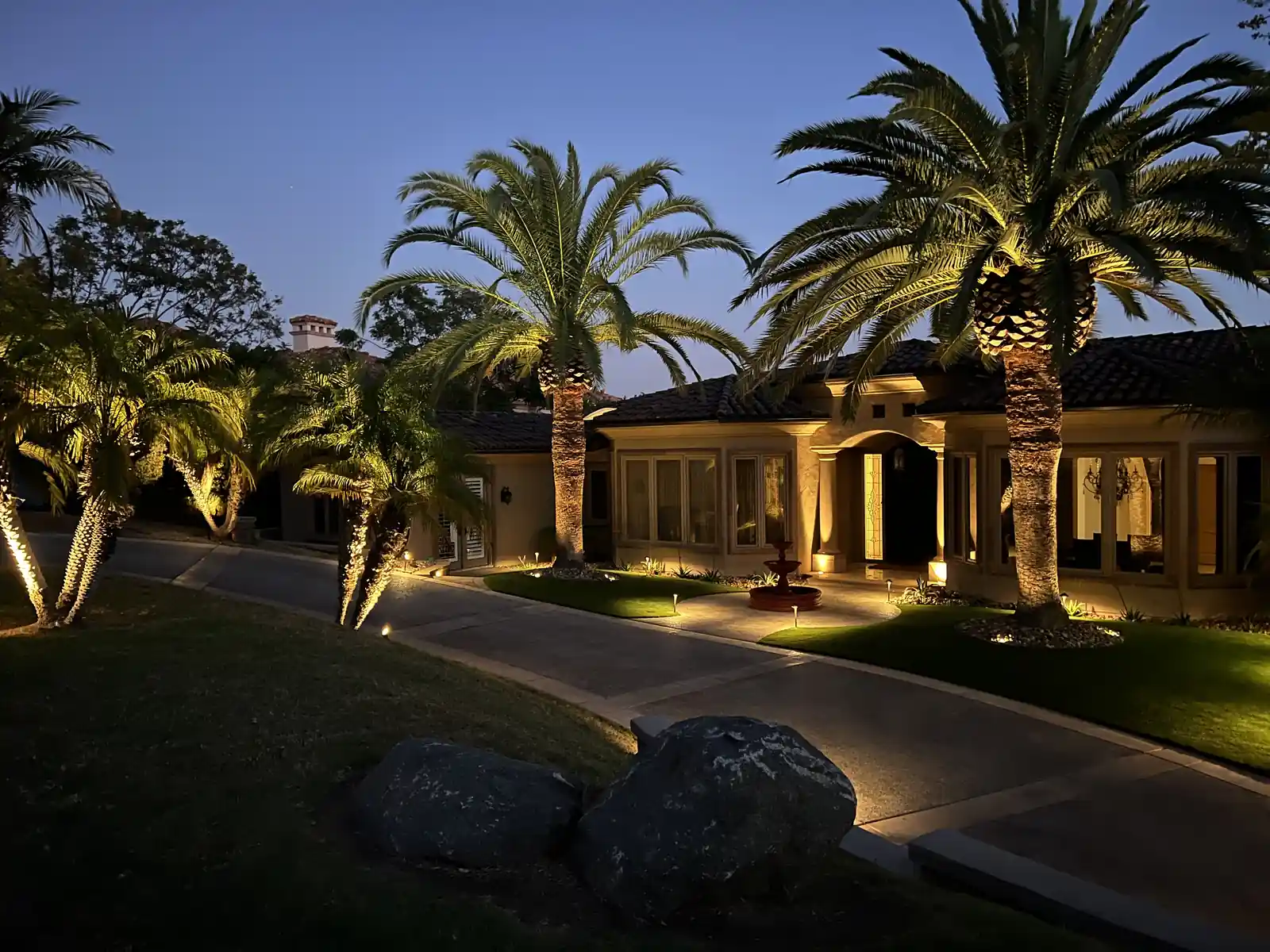 Front-yard lighting on palm trees and a home facade at dusk by Panjia Outdoors