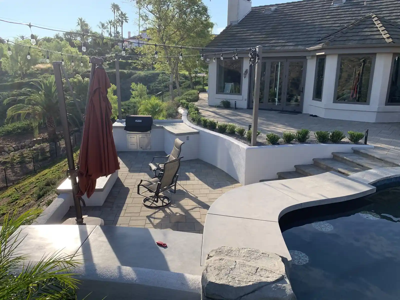 Outdoor kitchen with built-in grill and string lights by Panjia Outdoors