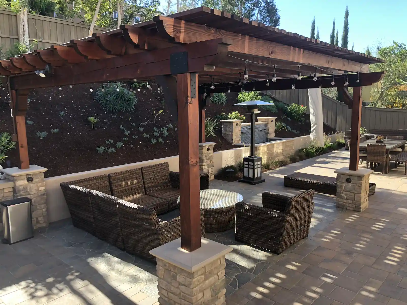Pergola lounge with string lights and stone columns by Panjia Outdoors
